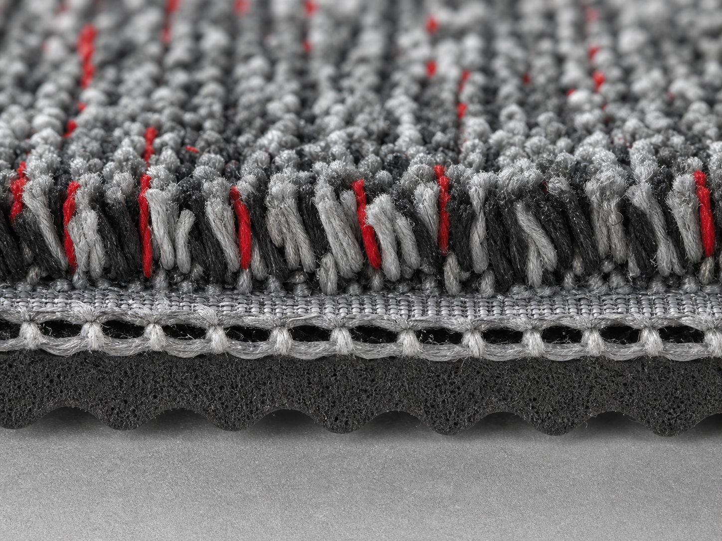 Close-up cross section of bonded carpet fibres and backing